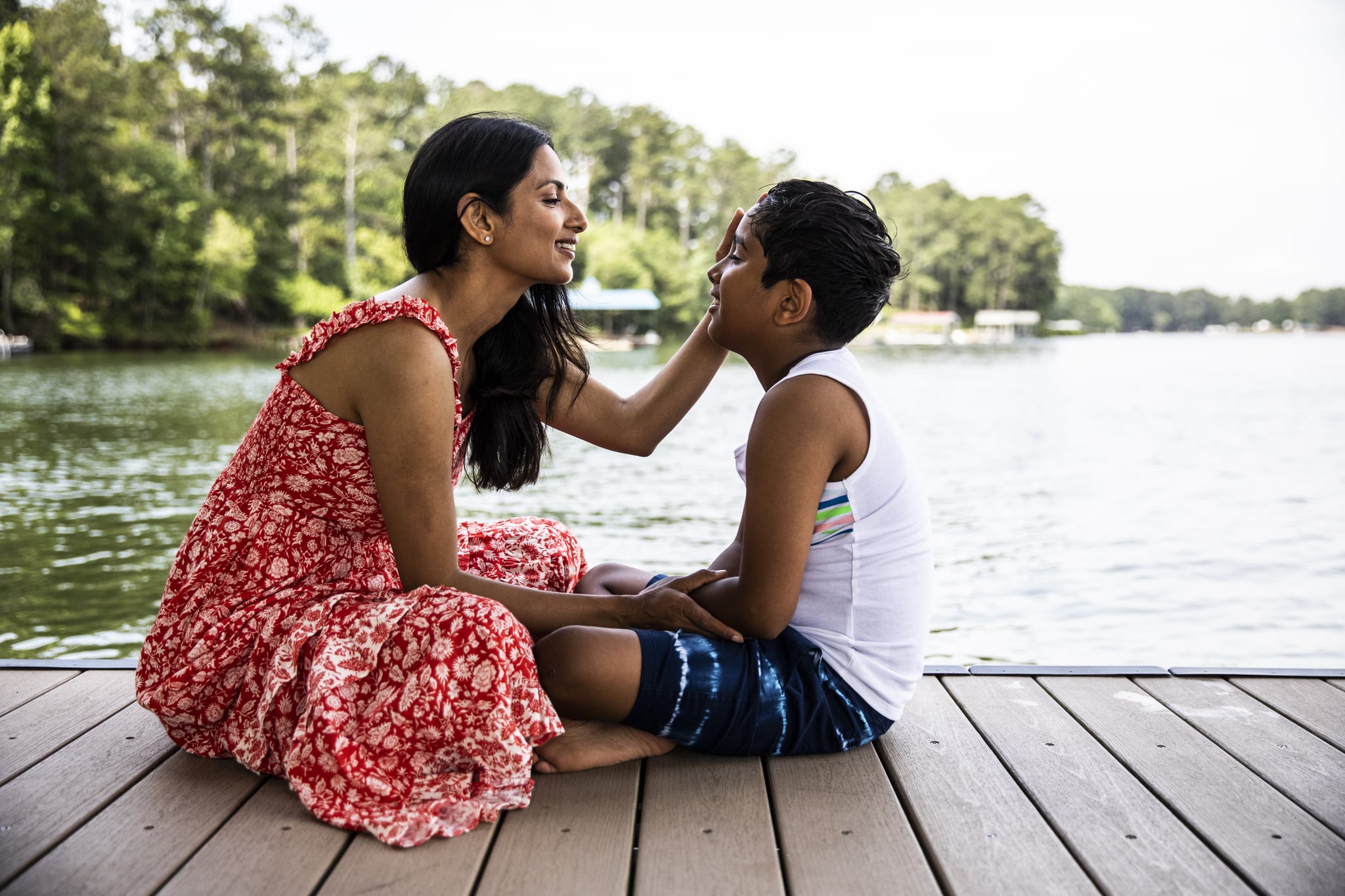 Mother and son embracing on dock at lake