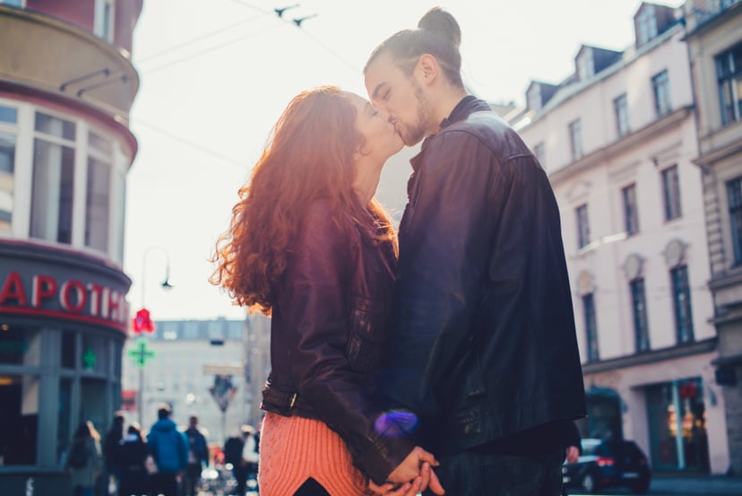Young couple kissing in the city in backlight.