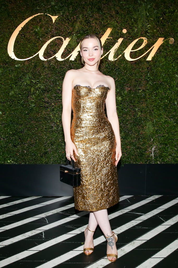 We hate to break it to ya, Zeus, but Dove Cameron is coming for your title as the ruler of Mount Olympus. The actress and singer exuded major goddess energy while attending a launch party for Cartier's latest jewelry collections in Los Angeles on Tuesday, wearing gold from head to toe. (No, literally — she even wore a shiny hair tie.) 
For the fancy gathering, Dove slipped into a Dundas bustier top and knee-length skirt set that paired so perfectly together, it looked like a dress, both made with a textured brocade finish for an extra luxe touch. Although Dove's lace-trimmed top was technically designed with two spaghetti straps, she either tucked them in or removed 'em entirely to create a strapless look. She styled her subtly sexy outfit with a gold necklace and two rings from the new Clash de Cartier collection, plus metallic ankle-strap heels, a black top-handle bag by Tyler Ellis, and gold eye makeup. 
Read ahead for a closer look at Dove's latest head-turning fashion moment, and join us in bowing down to her regal highness.

    Related:

            
            
                                    
                            

            Dove Cameron Opens Up About Coming Out as Queer and "Choosing to Love Myself"