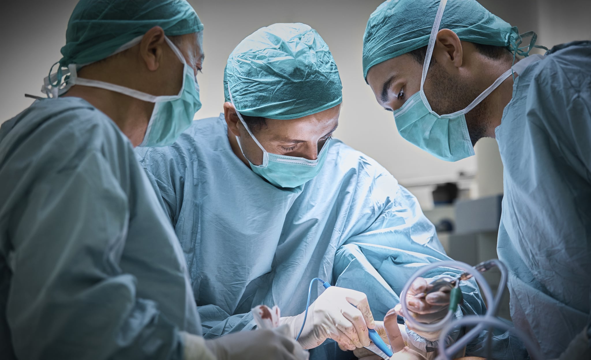 Plastic surgeons operating patient for breast implant. Team of doctors are in scrubs at operating room. They are at hospital.