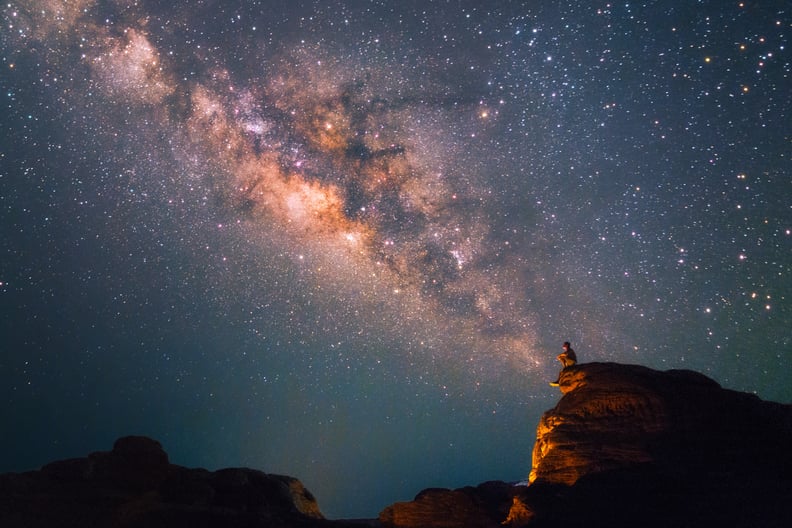 Silhouette man sits on the top of rock looking at the beautiful Milky Way Stars at the Grand Canyon of Thailand (Sam Phan Bok)