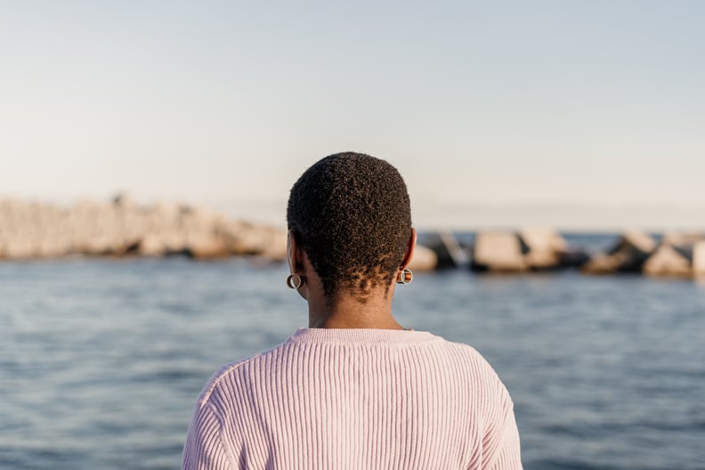 Rear view of a Black woman looking at the sea, looking relaxed.