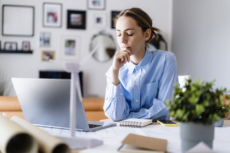 Woman with closed eyes in office with wind turbine model on table