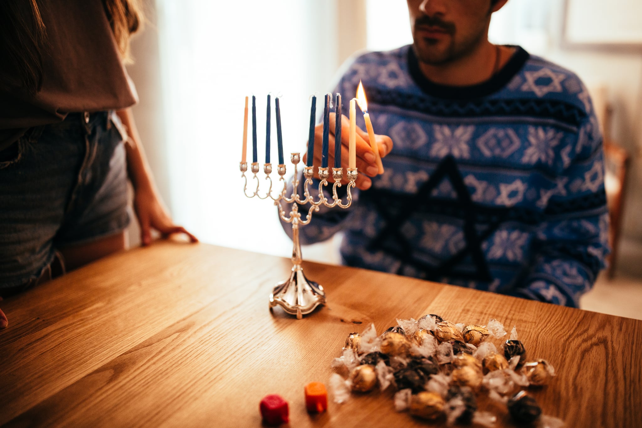 A couple lights a Hanukkah menorah together to celebrate Hanukkah traditions and reconnect with their culture.