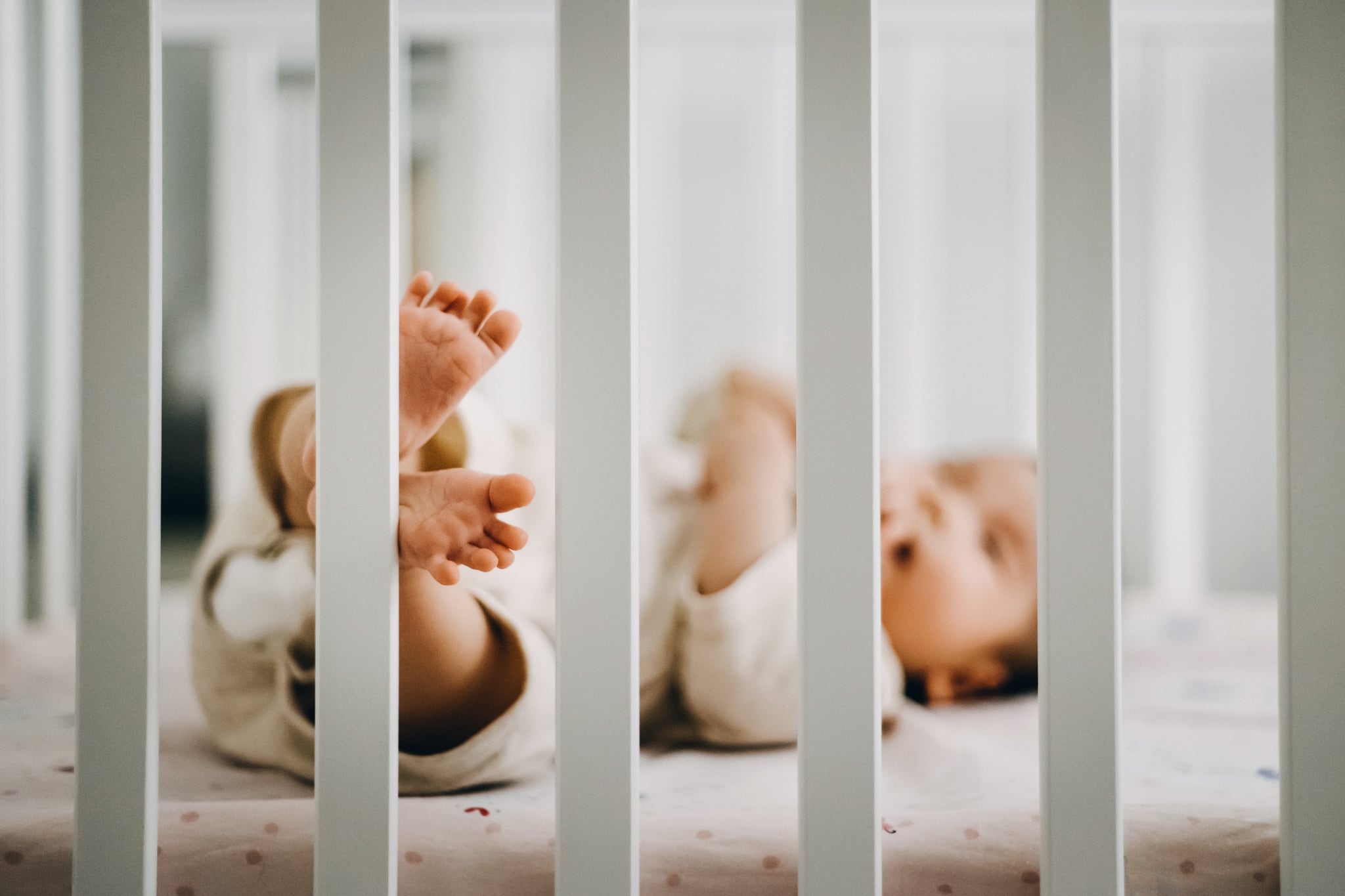 Baby sleeping in cot, little feet stepping on the fence of cot