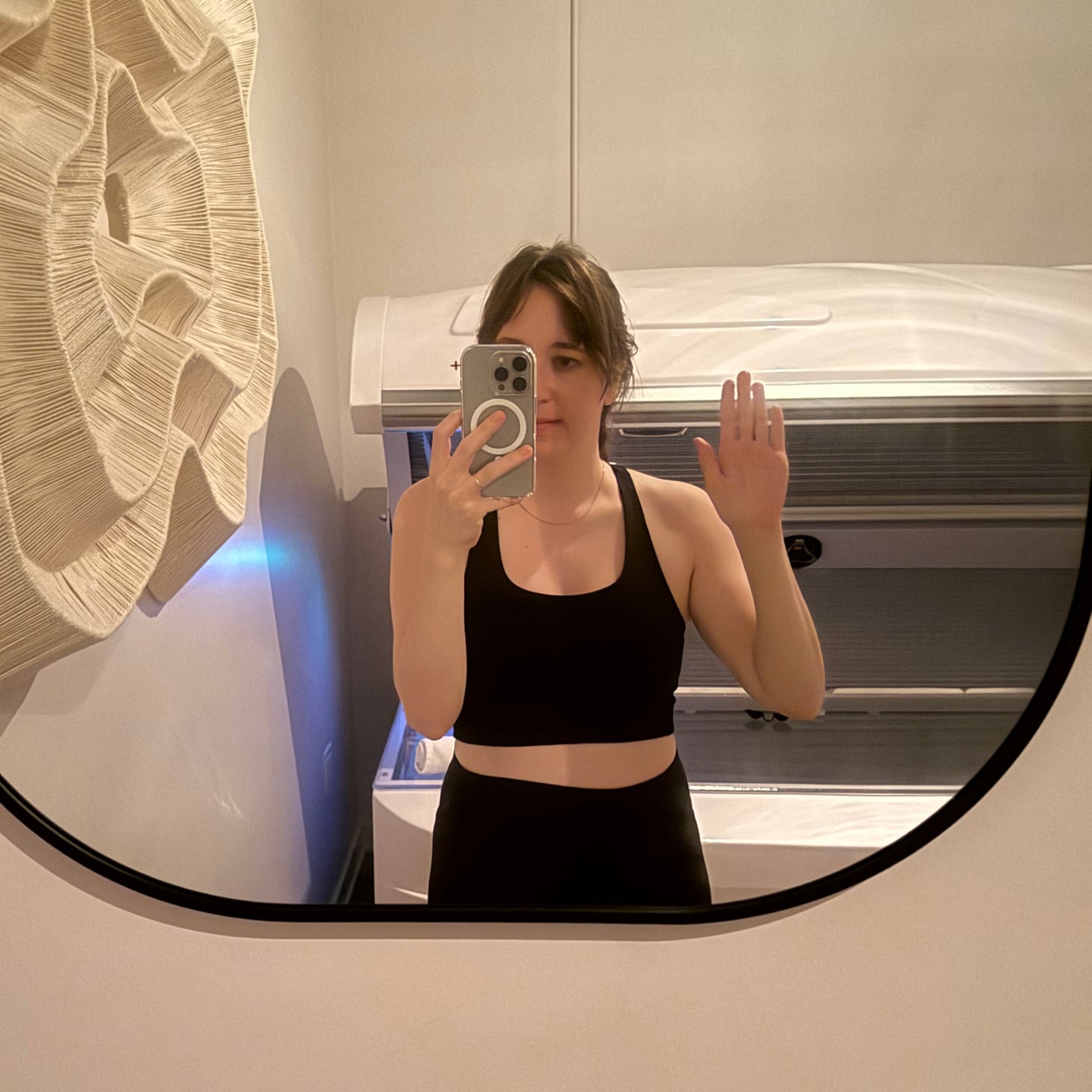 PS Health and Fitness Director Mirel Zaman waves in the mirror after a red light therapy session at Continuum Club