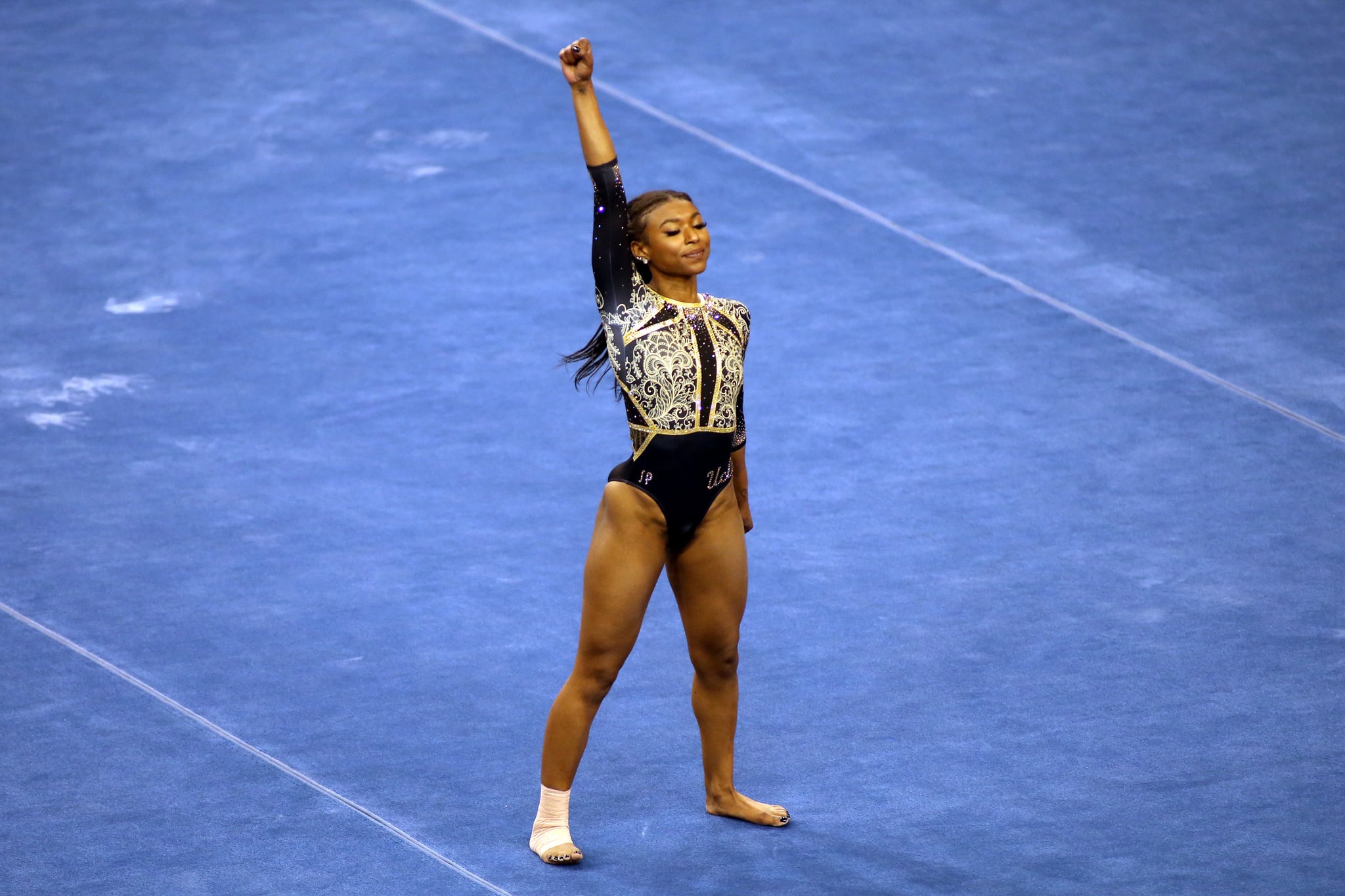 LOS ANGELES, CALIFORNIA - FEBRUARY 27: Nia Dennis of the UCLA Bruins raises a fist during her floor routine during a meet against the Oregon State Beavers at Pauley Pavilion on February 27, 2021 in Los Angeles, California. (Photo by Katharine Lotze/Getty Images)