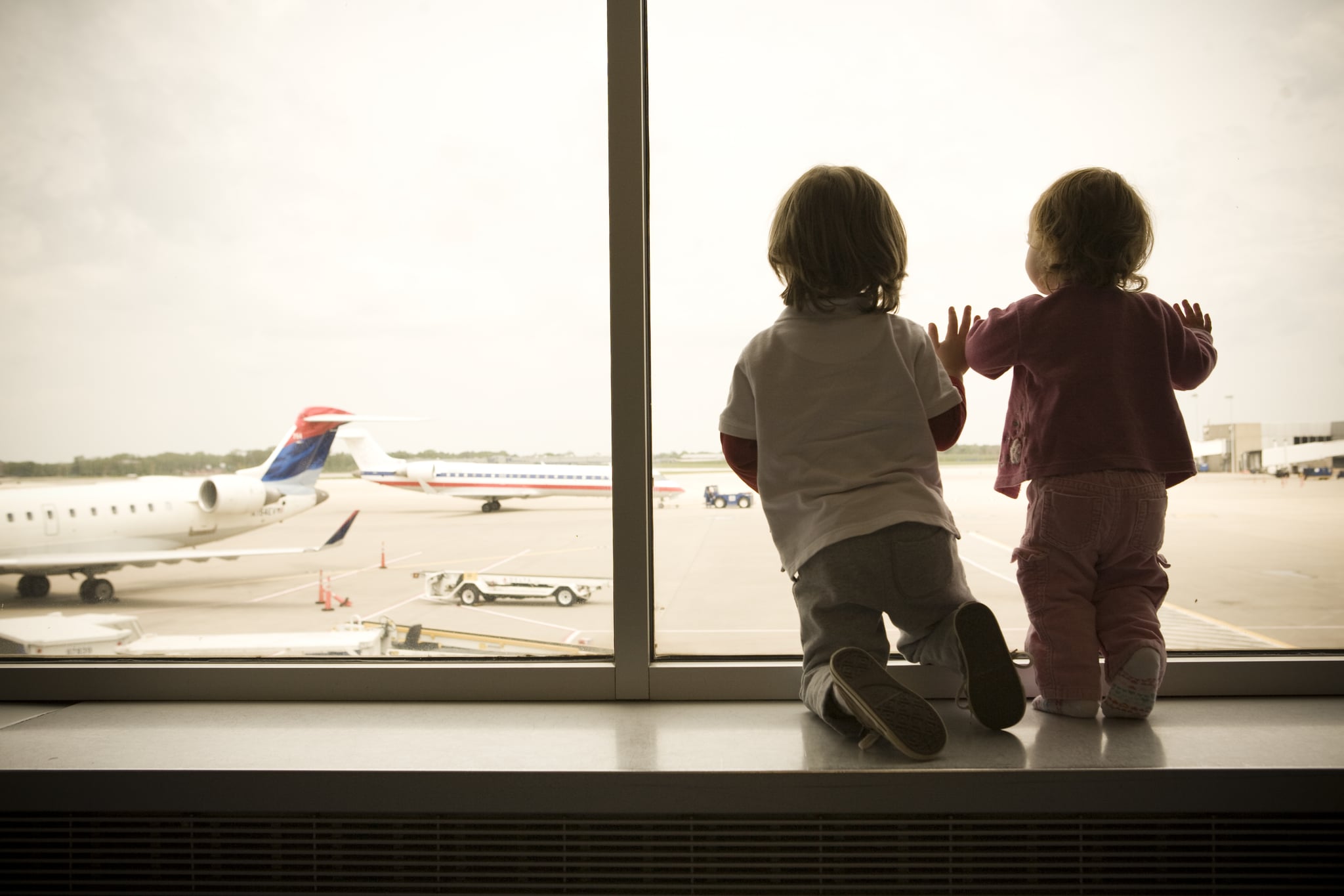 Two Children Excitedly Watch as Planes Land at the Airport