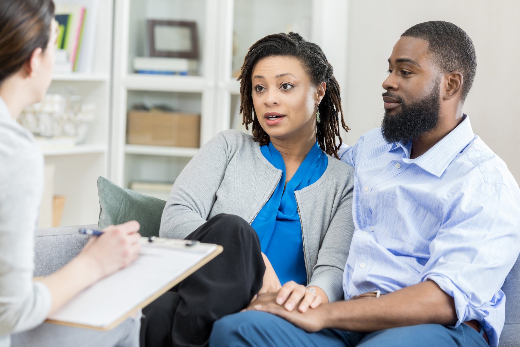 Mid adult couple talk with female counselor about problems in their marriage.