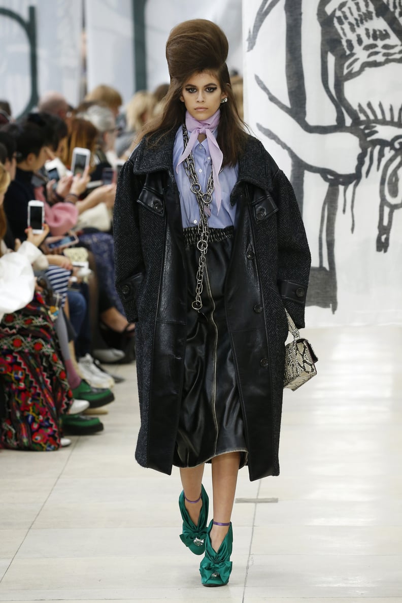When Kaia Walked For Miu Miu, She Wore a Chambray Shirt, Leather Midi Skirt, Oversize Coat, and Green Heels