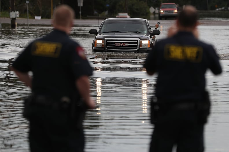 Two officials watch as a truck drives through the flood.