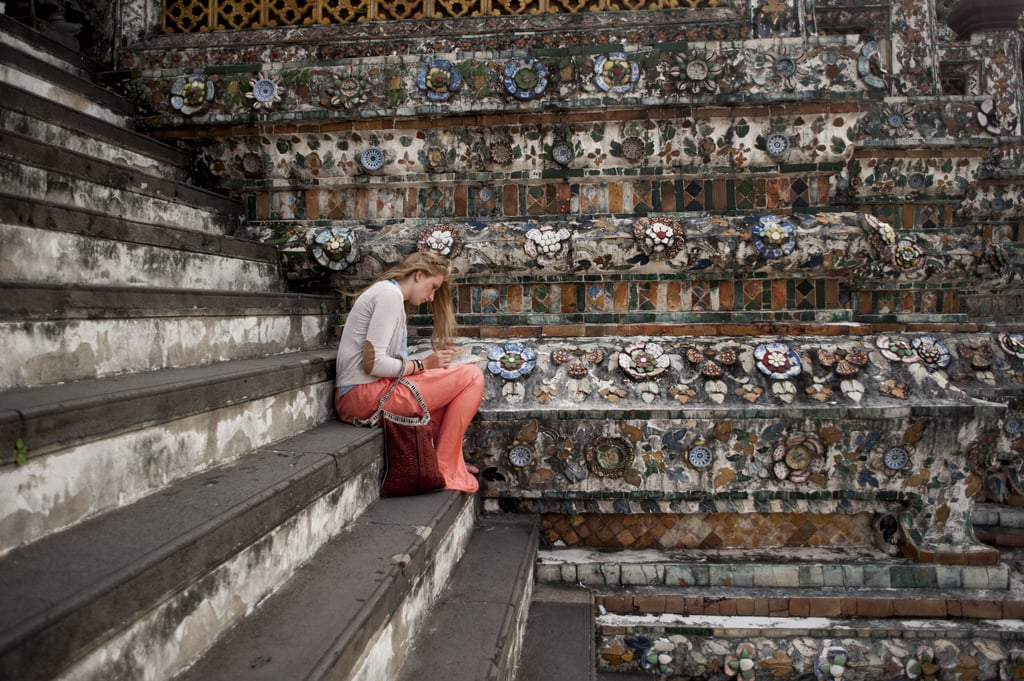 A tourist read on the steps of a temple in Bangkok, Thailand.