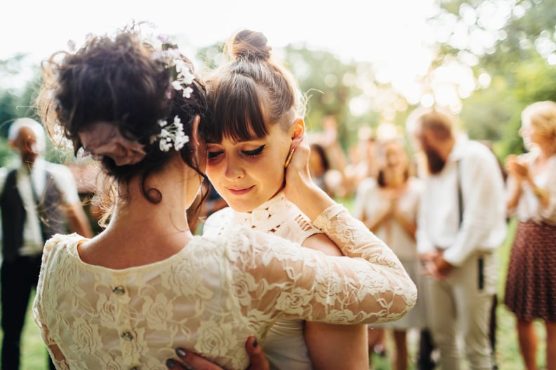 Newlywed lesbian couple dancing together the first dance after their wedding ceremony. Family and friends are visible in the background