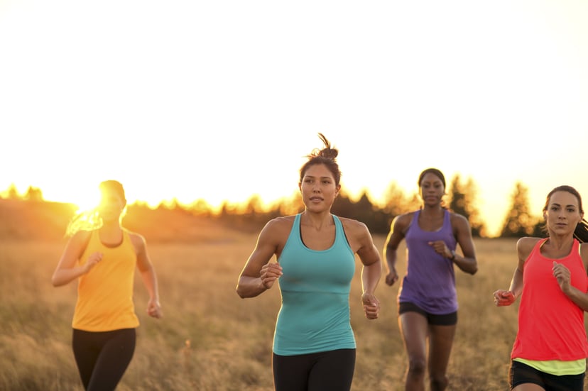 Group of diverse adult females trail running as the sun sets behind them