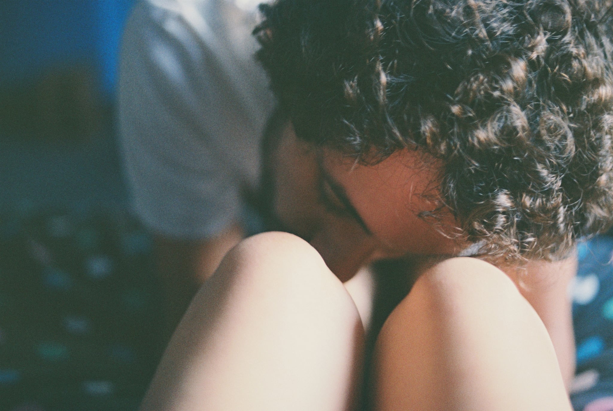 Man Kissing Woman's Knees on Bed