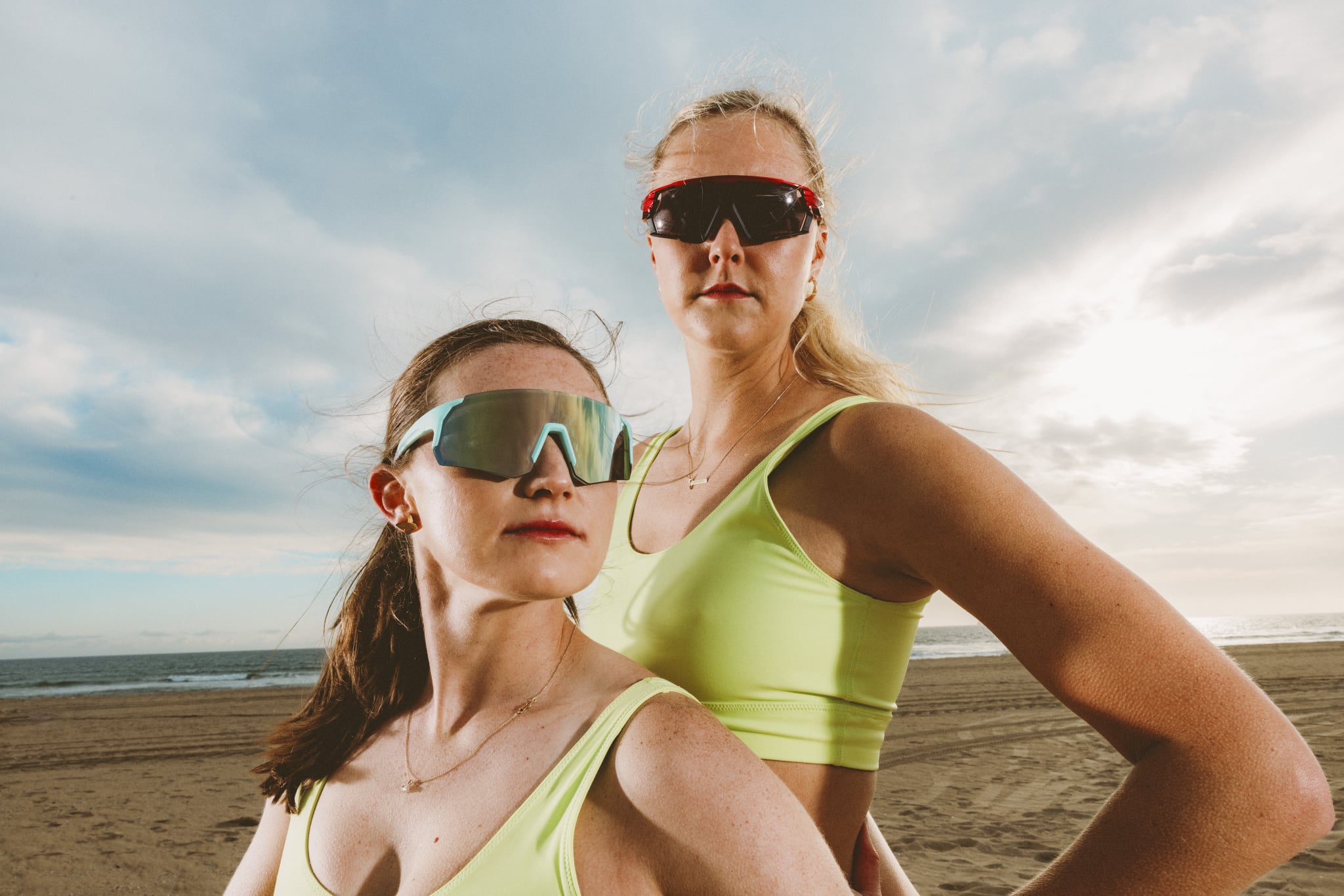 Kristen Nuss and Taryn Kloth posing by the beach in matching sports bras and Zenni Optical sunglasses.
