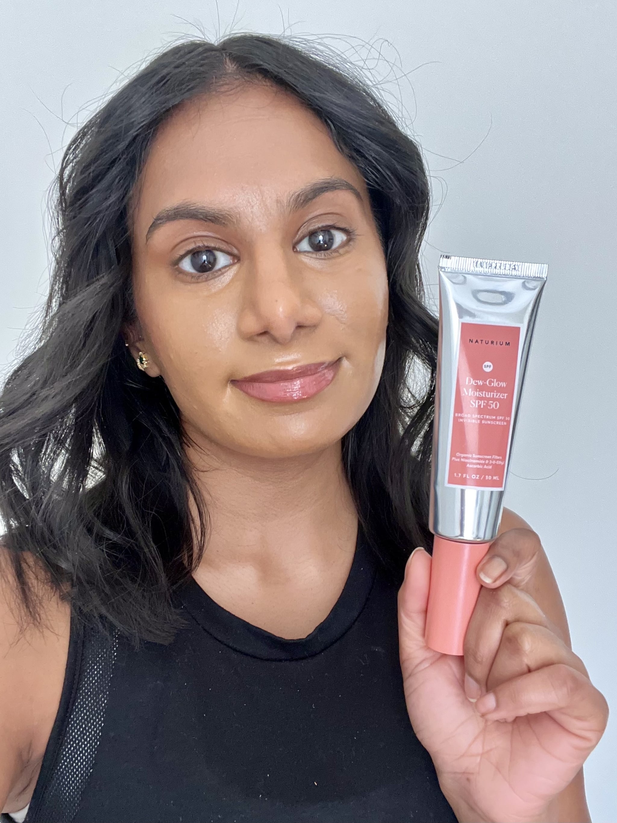 Woman holding the Naturium Dew Glow Moisturiser SPF 50.