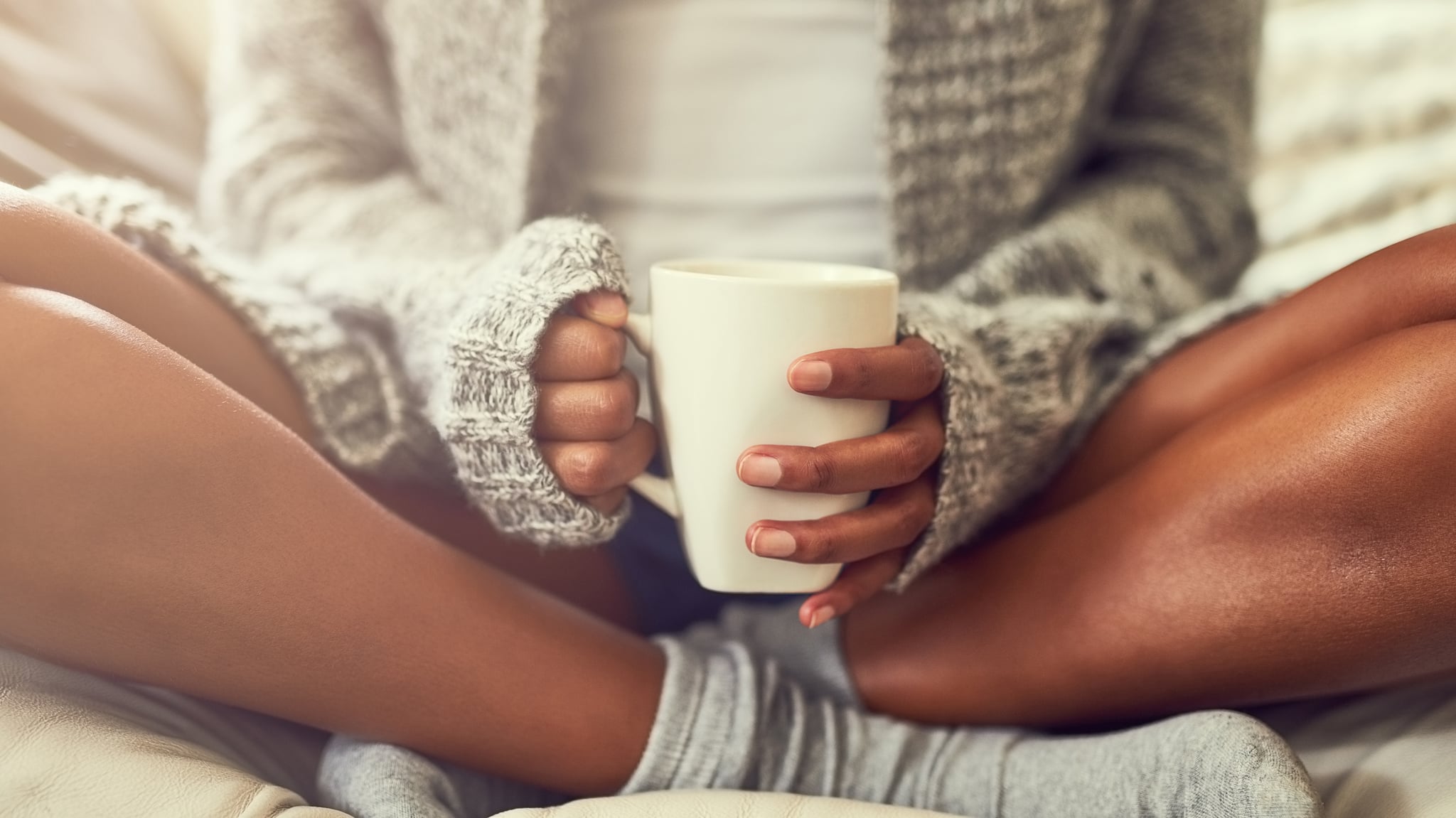 Shot of an unidentifiable young woman enjoying a cup of coffee while sitting on her couch at home