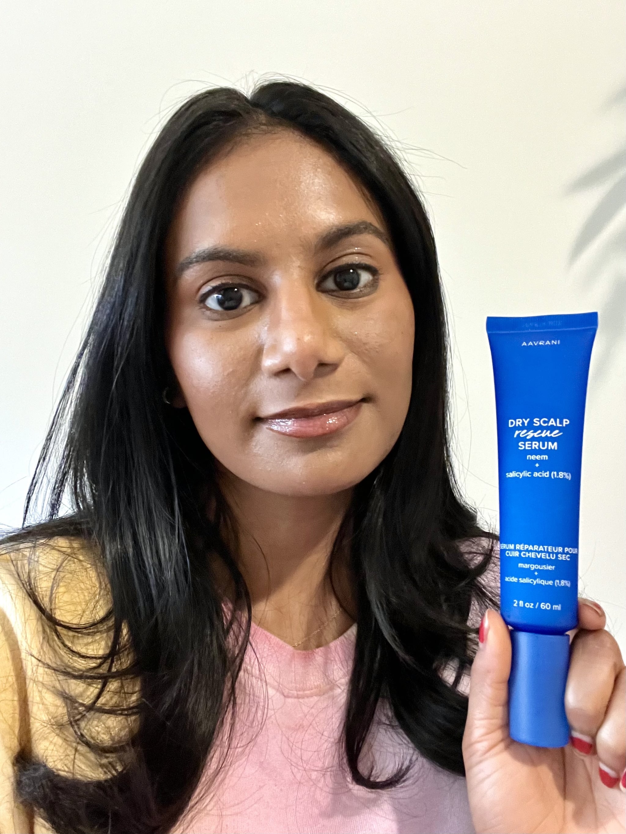 Woman holding the Aavrani Anti-Dandruff Dry Scalp Rescue Serum.