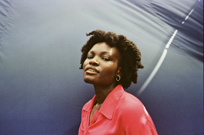 Woman With Curly Hair Posing Against Blue Backdrop