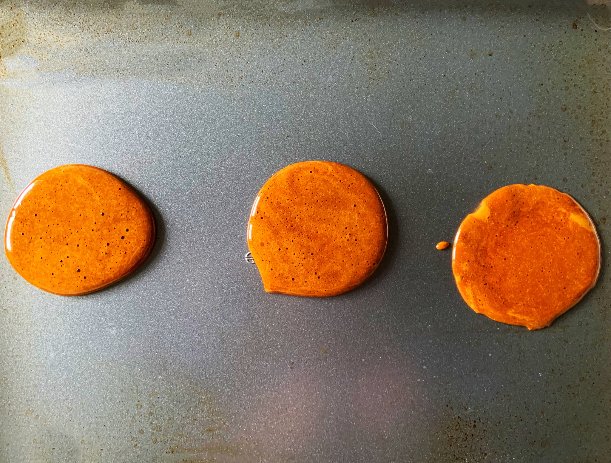 Three circles of the dalgona candy on a baking sheet