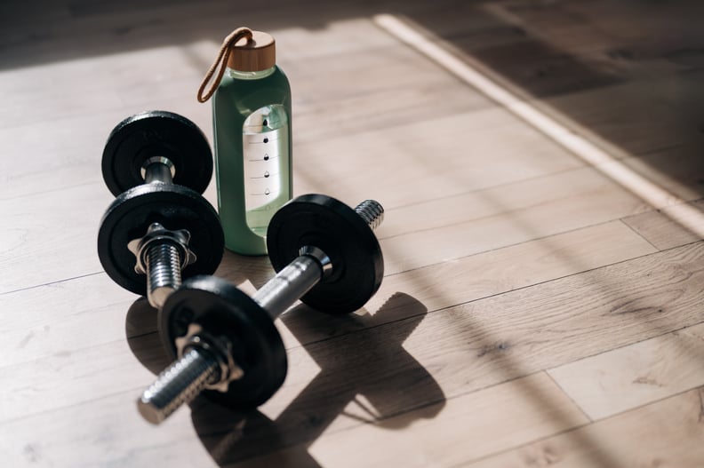 Close up of dumbbells and water bottle on the yoga mat