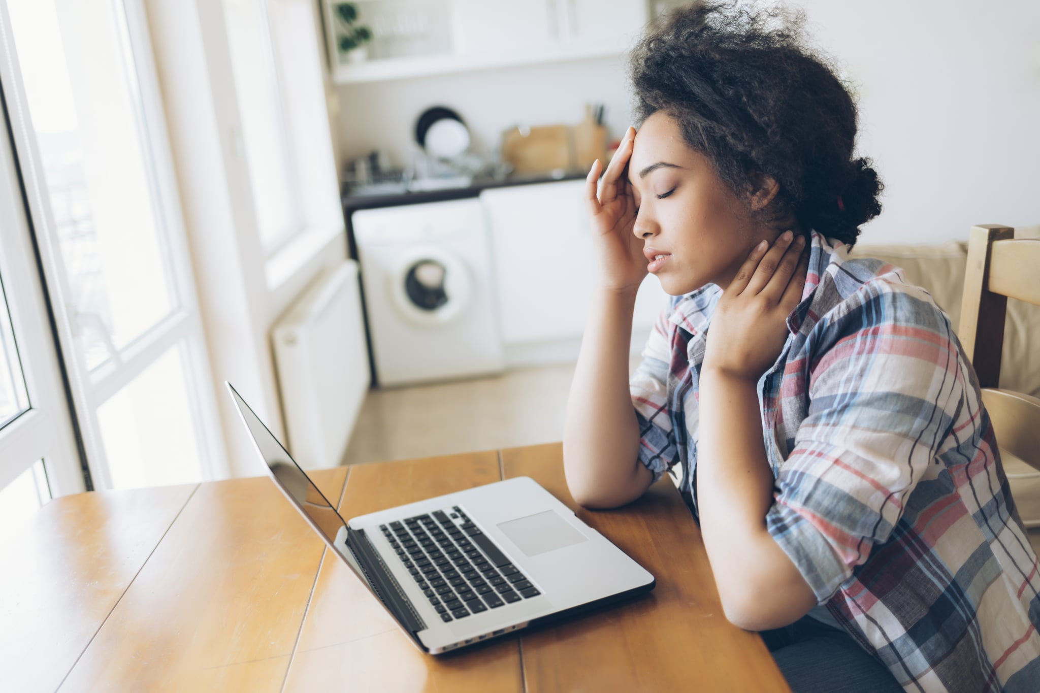 Woman using laptop and having headache.