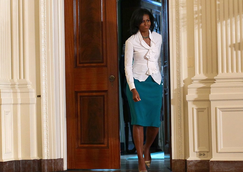For a White House speaking event, Michelle chose a white ruched blouse with a teal skirt and nude pointy-toe pumps.
For a White House speaking event, Michelle chose a white ruched blouse with a teal skirt and nude pointy-toe pumps.