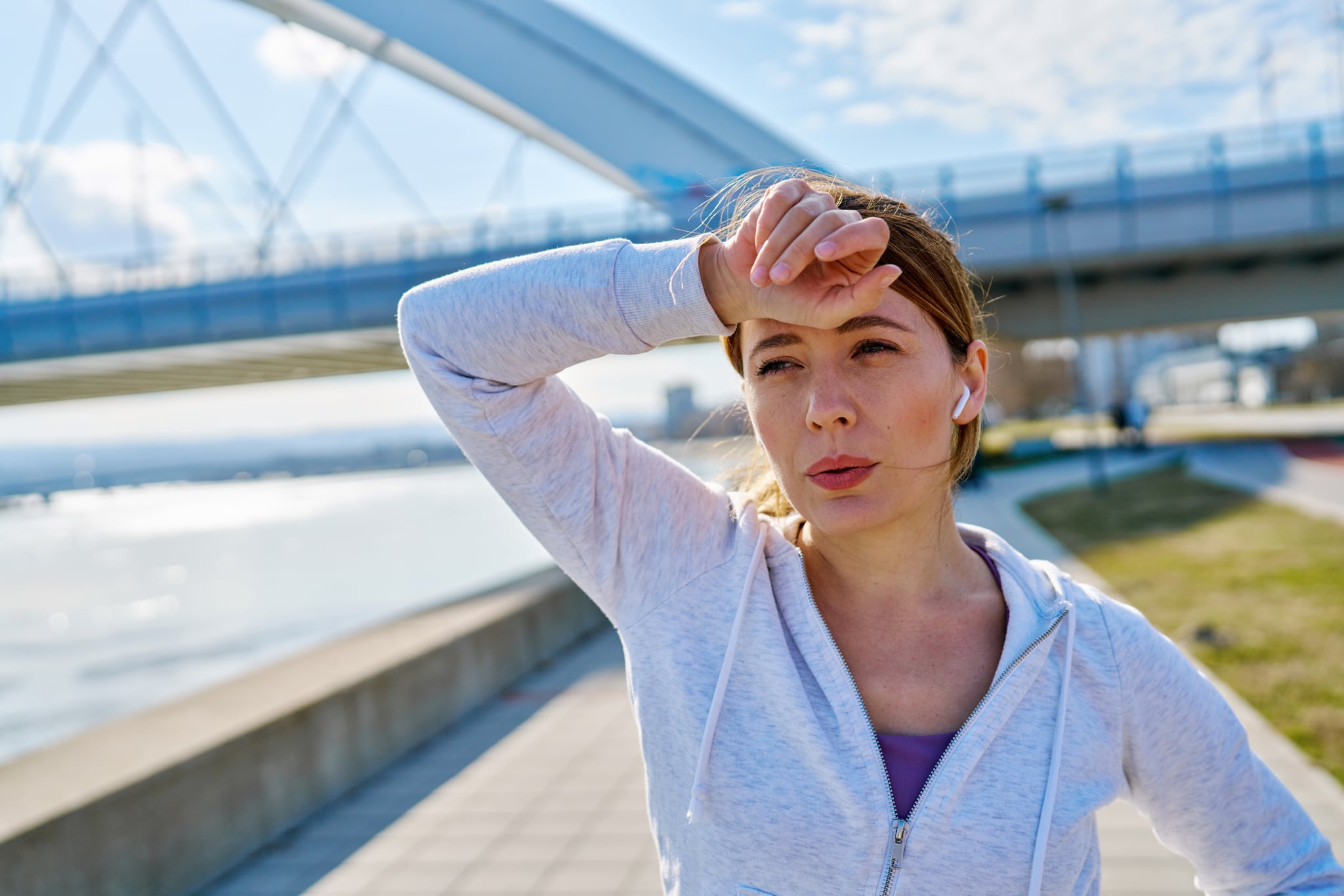 Young sportswoman taking a break from her workout, wiping sweat from her forehead.