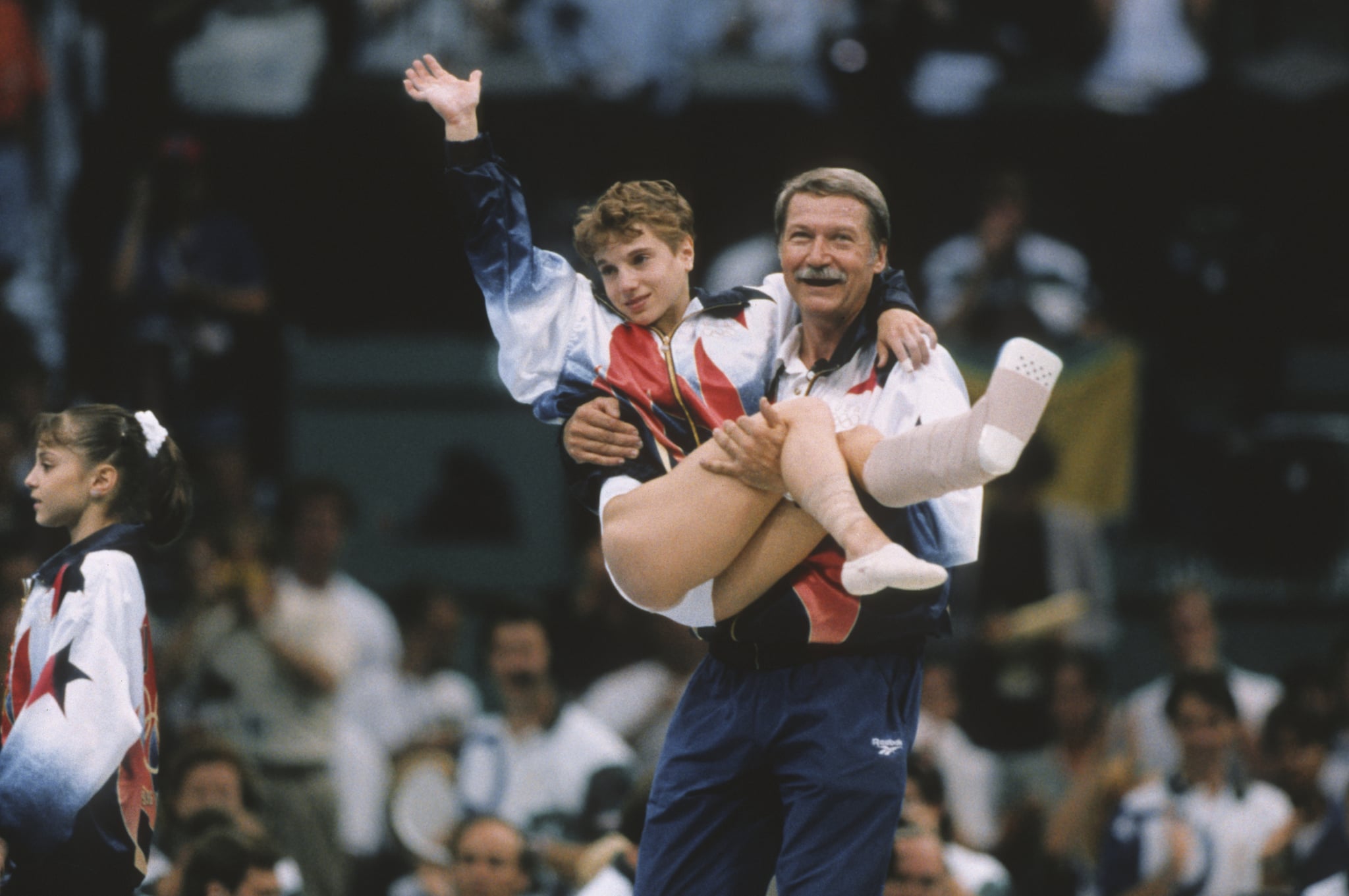 ATLANTA - JULY 23:  Kerri Strug of the United States is carried by coach Bela Karolyi during the team competition of the Women's Gymnastics event of the 1996 Summer Olympic Games held on July 23, 1996 in the Georgia Dome in Atlanta, Georgia.  Strug was part of the gold medal winning USA Women's team, nicknamed the Magnificent Seven.  (Photo by David Madison/Getty Images)