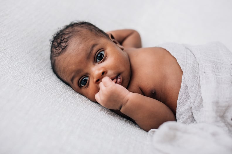 Beautiful African-American newborn little boy just a few weeks old swaddled in a cream colored soft blanket with copy space