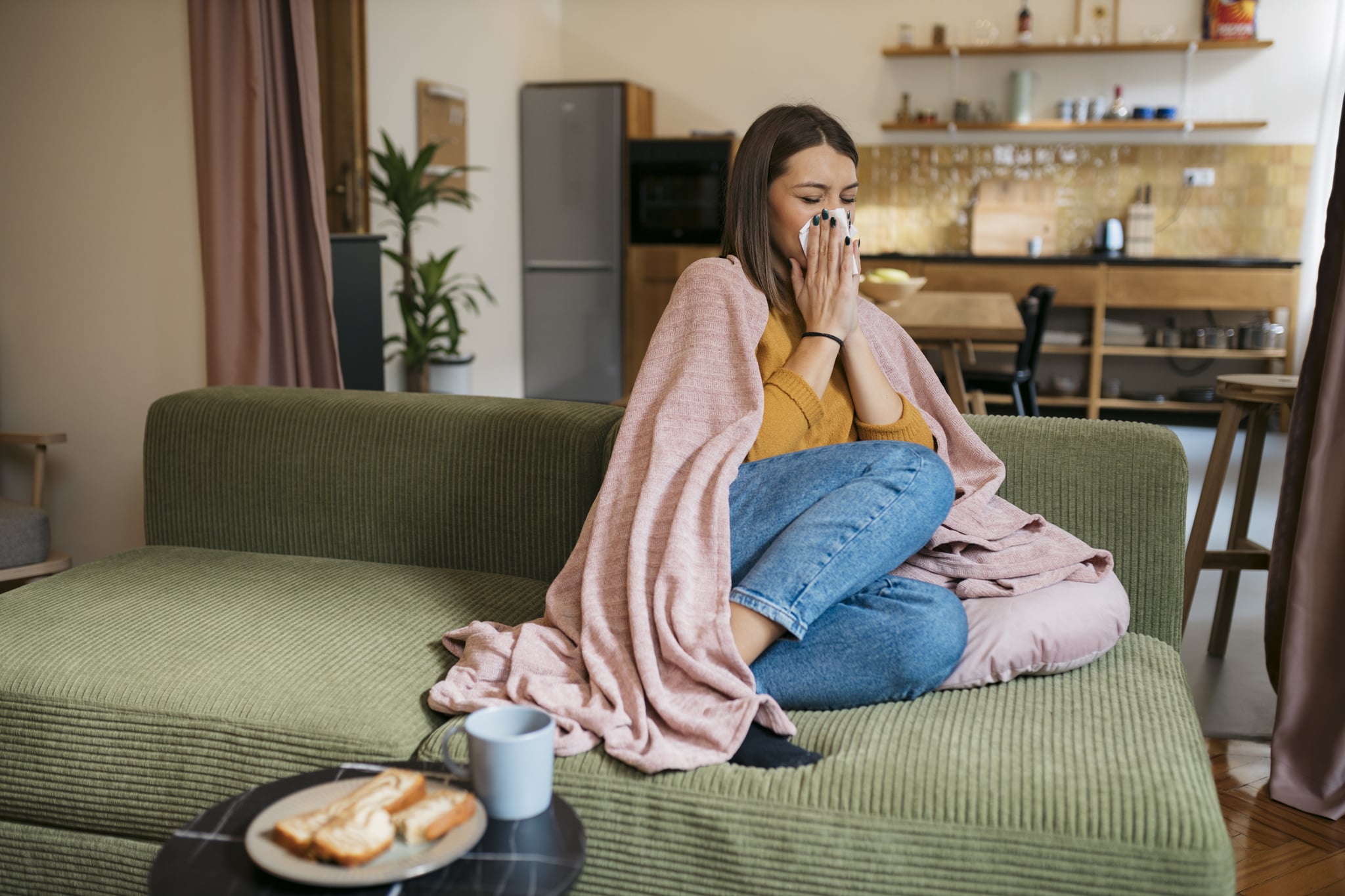 Woman sick on the couch, deciding what foods to eat when sick. Woman sick on the couch, deciding what foods to eat when sick.