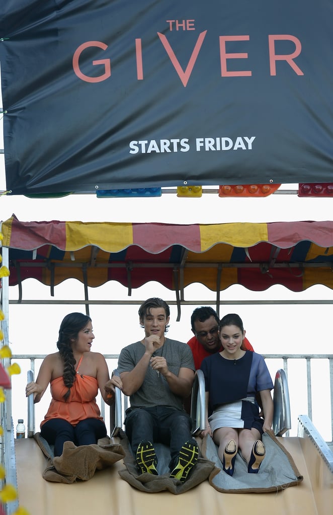 The Giver costars Maity Interiano, Brenton Thwaites, and Odeya Rush took a ride down a giant slide while promoting their new movie in Miami on Thursday.