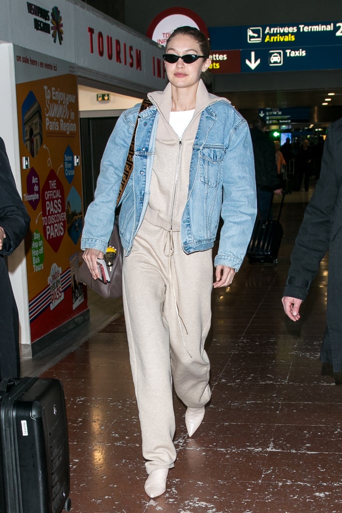 At an airport wearing a tan Sally LaPointe sweatsuit with Stuart Weitzman shoes, a Levi's denim jacket, and a Fendi duffel bag.