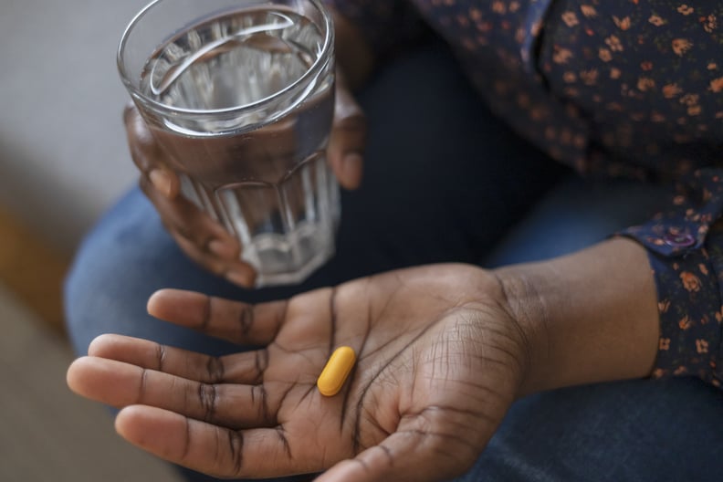 关闭非裔美国妇女从瓶子,取出药丸补充剂或抗生素,女性准备采取紧急医学、慢性疾病、医疗保健和治疗的概念