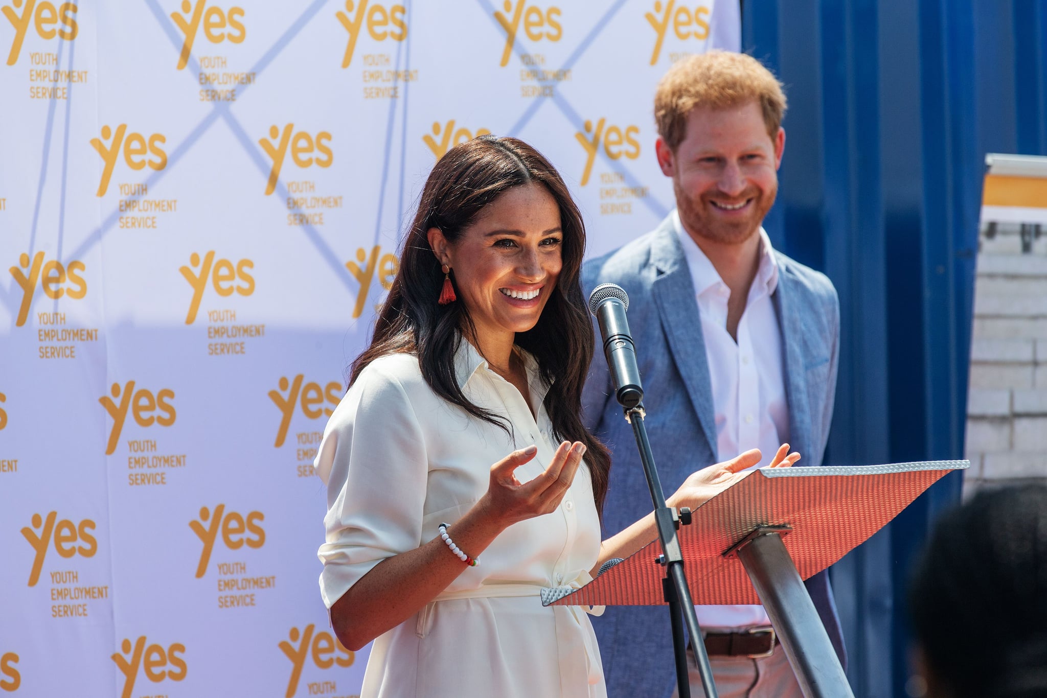 Meghan, Duchess of Sussex(L), is watched by Britain's Prince Harry, Duke of Sussex(R) as  she delivers a speech at the Youth Employment Services Hub in Tembisa township, Johannesburg, on October 2, 2019. - Meghan Markle is suing Britain's Mail On Sunday newspaper over the publication of a private letter, her husband Prince Harry has said, warning they had been forced to take action against 