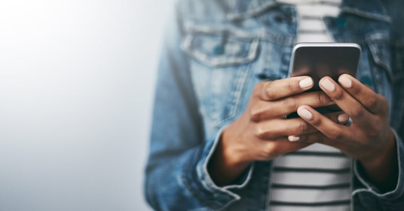 Studio shot of an unrecognizable young woman using her cellphone against a grey background