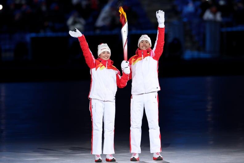 Torch bearers Dinigeer Yilamujiang and Jiawen Zhao of Team China hold the Olympic flame during the Opening Ceremony of the Beijing 2022 Winter Olympics