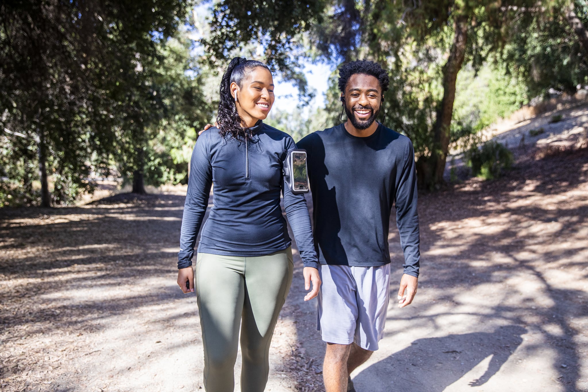 A black man and Latina woman walking on a trail after a workout