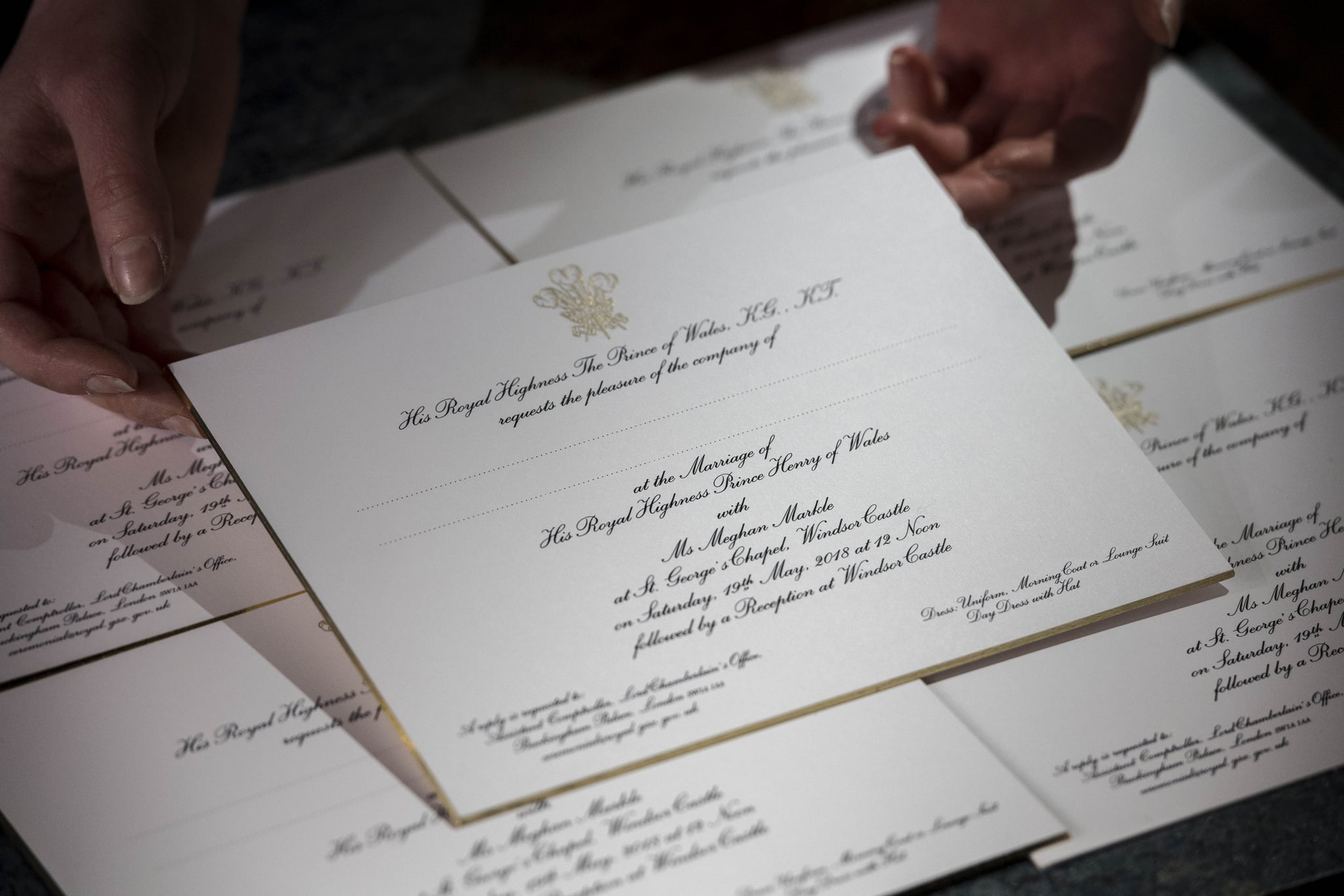 LONDON, ENGLAND - MARCH 22:  Hands hold invitations just printed at the workshop of Barnard and Westwood for Prince Harry and Meghan Markle's wedding on March 22, 2018 in London, England. The couple will marry in St. George's Chapel at Windsor Castle on May 19.  (Photo by Victoria Jones - WPA Pool/Getty Images)