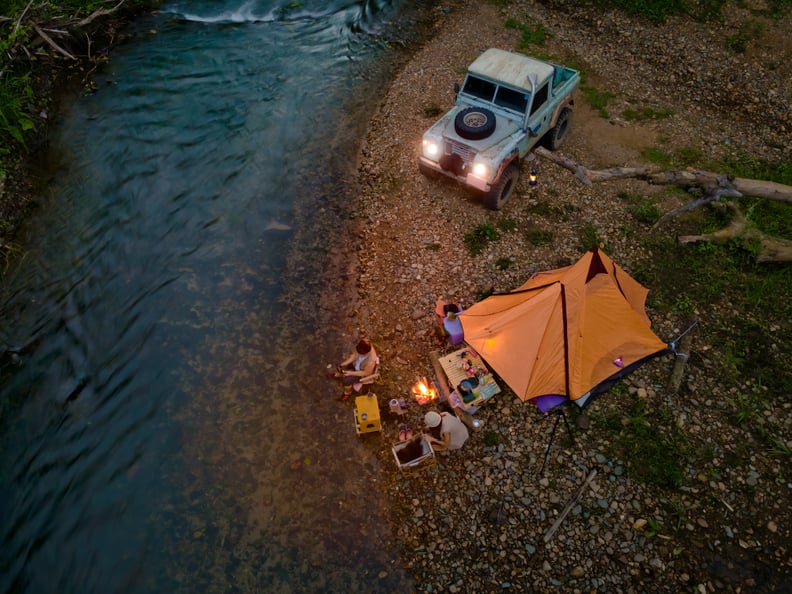 a tent and campfire next to a river