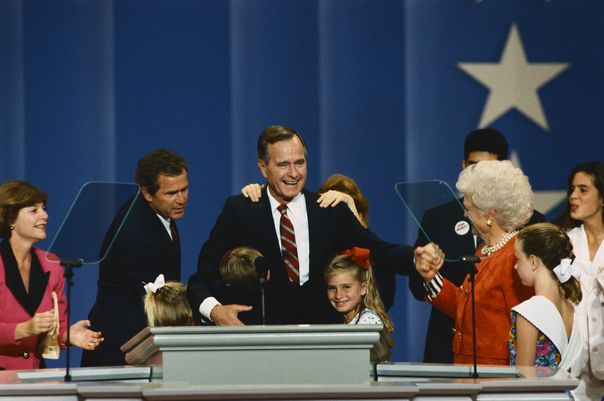 George Bush on the podium at the 1992 Republican National Convention. He is joined by (left to right) daugther-in-law Laura Bush, her husband George W., and her daughter Jenna, an unidentified grandson hugging the President, granddaughter Barbara, wife Barbara, and grandchildren George Prescott (behind Barbara), Lauren, and Noelle. (Photo by © Wally McNamee/CORBIS/Corbis via Getty Images)