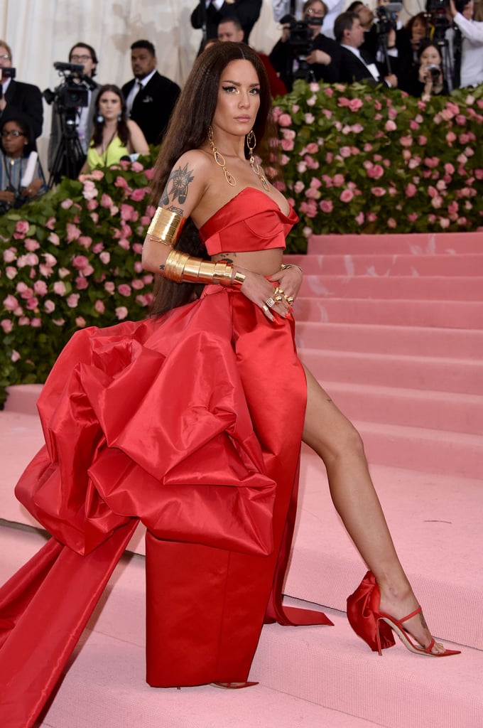 Gal Gadot might have been an amazing Wonder Woman, but Halsey's look at the 2019 Met Gala already has us considering her for any reboots in the future. The 24-year-old singer stepped out onto the pink carpet for the first time on Monday in a bright red Atelier Prabal Gurung two-piece gown with a full-length slit skirt and matching pointy-toed shoes. In addition to her brilliant candy-apple-red nails and gorgeously crimped hair, Halsey decided to dress up the outfit even more with a few gold accessories, and by a few, I mean dozens. 
Decorated with at least 10 Jennifer Fisher gold cuff bracelets on each arm, matching armbands, and chunky gold rings on every finger, Halsey gave us all the glamour and presence of a true superhero on the red carpet. She finished off the look with a pair of dangling chain-link earrings, and we already know we'll be thinking about her outfit for days. See pictures of Halsey's Met Gala look ahead.

    Related:

            
            
                                    
                            

            Hello, Mattel? I Need a Kacey Musgraves Doll After Seeing Her Barbie-Inspired Met Gala Look