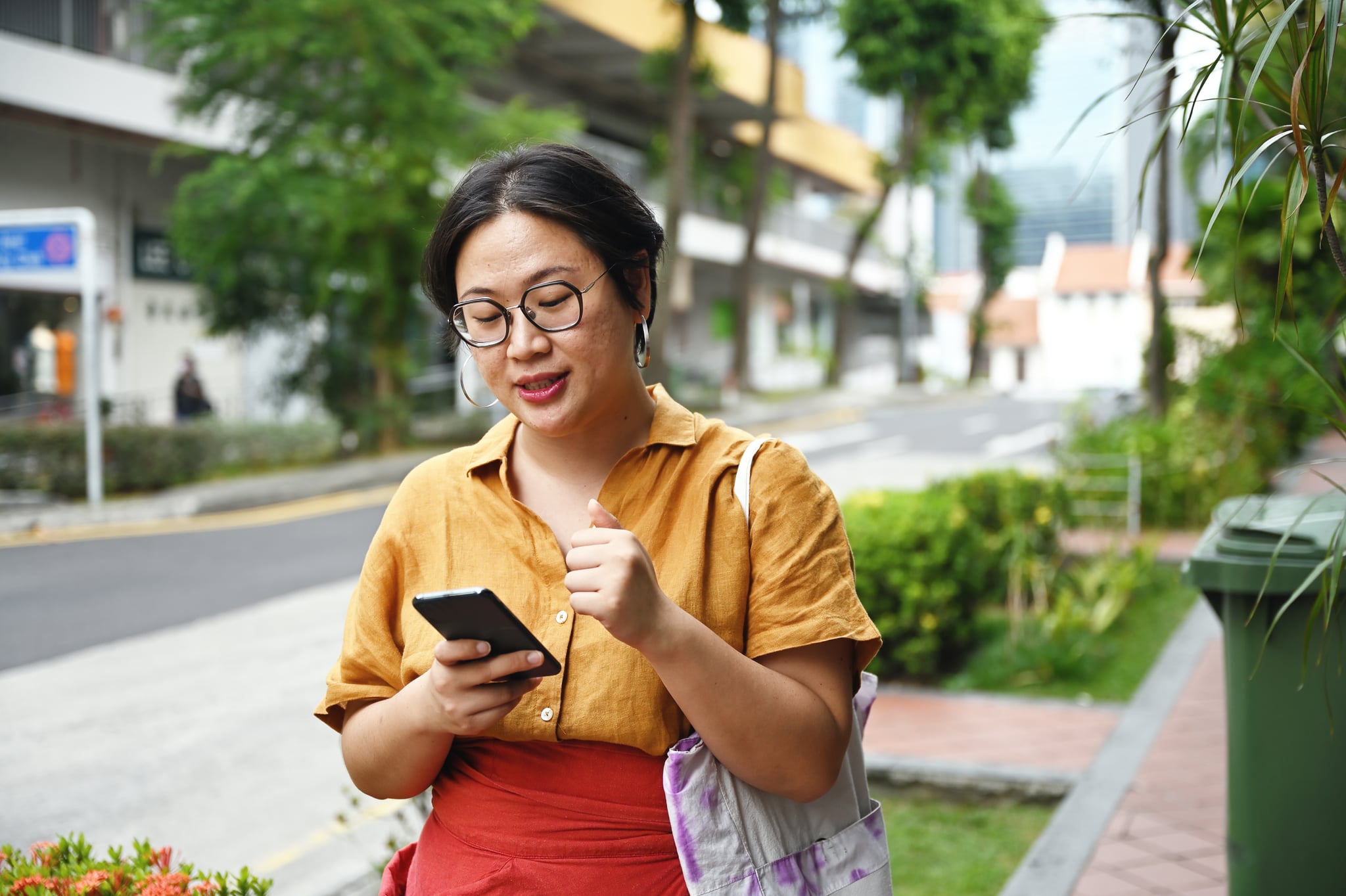 Woman Walking on Street and Looking at Phone