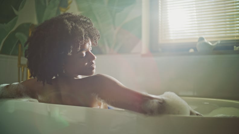 Woman lying in a bathtub, relaxing in hot water. Rear view