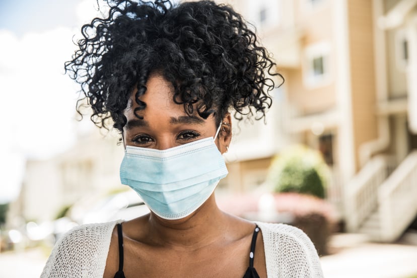 Young woman wearing surgical mask in front of home
