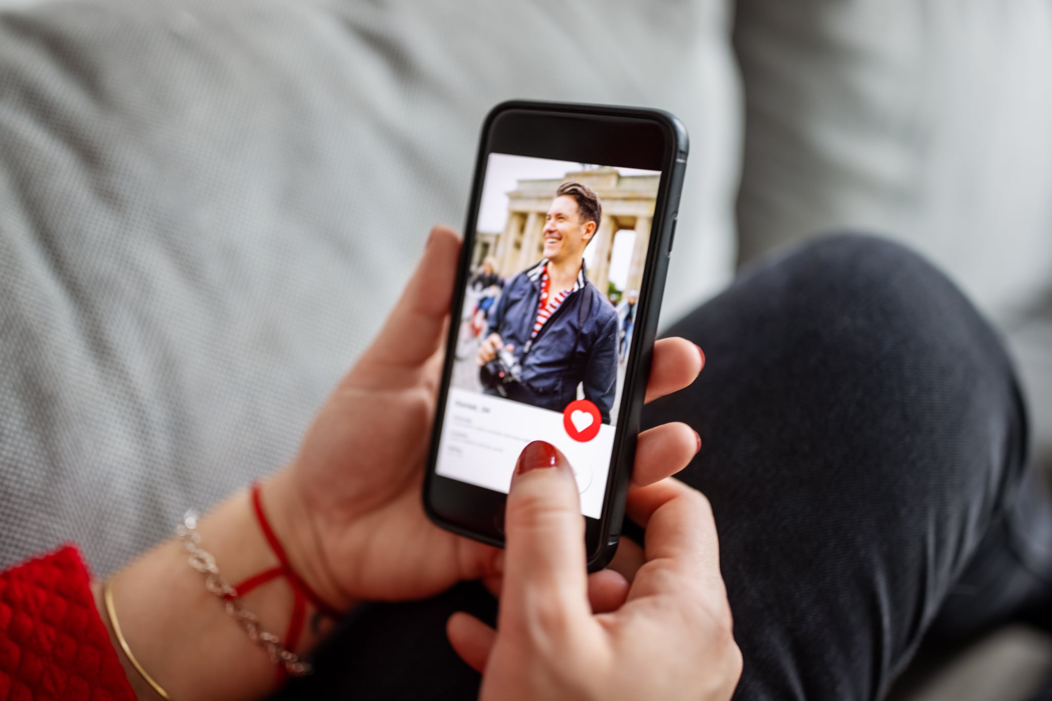 一名女性使用智能手机上的约会应用程序的特写。女人在手机上的在线约会软件上看着男人。