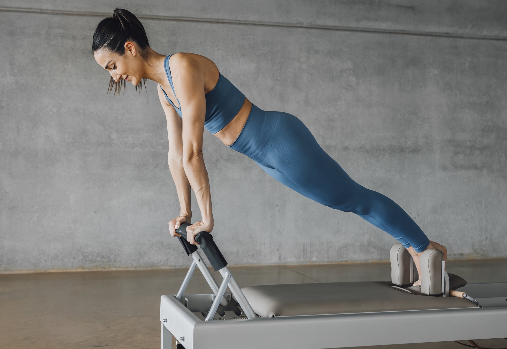 Woman performing a Pilates burpee on a reformer apparatus
