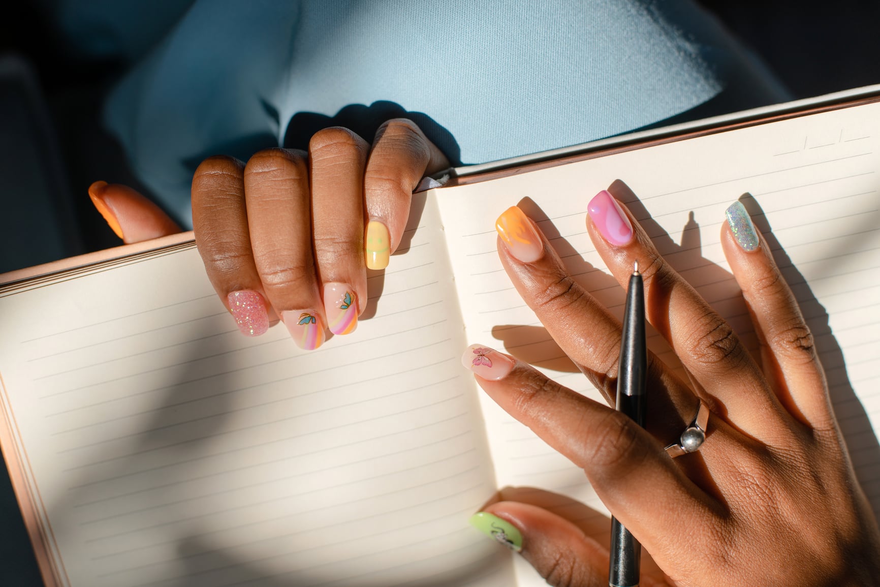Teenage girl with acrylic nails writing in her journal