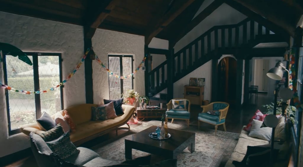 This living room, which Charli calls the party zone, has a high ceiling and large windows that flood the room with natural light. Charli decorated the room with brightly colored furniture, plants, and paper chains along the walls.